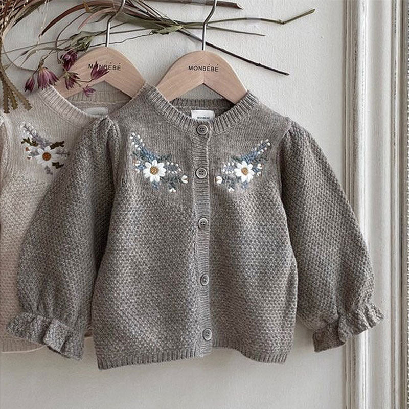 Grey knit baby cardigan with floral embroidery on a hanger
