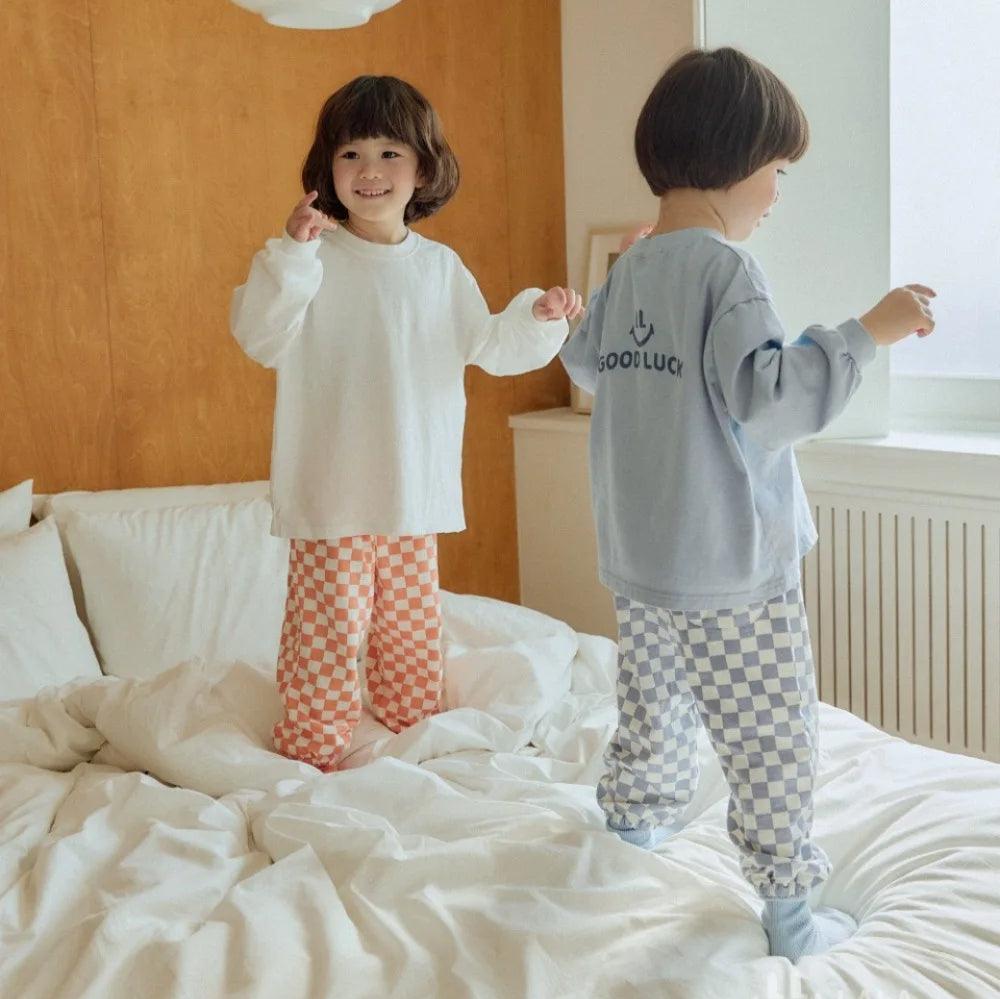 Two kids wearing orange and blue checkerboard pants