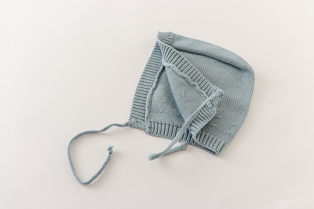 Side view of dusty blue knit baby bonnet with chin ties