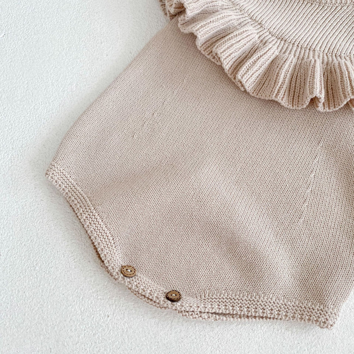 Close-up of ruffle collar and snap buttons on knit baby romper
