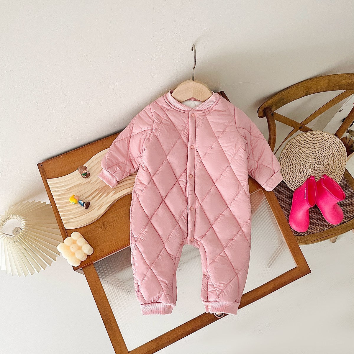 Pink diamond-quilted baby jumpsuit on a hanger
