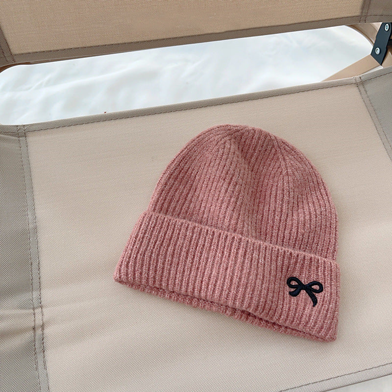Pink ribbed knit beanie with black bow