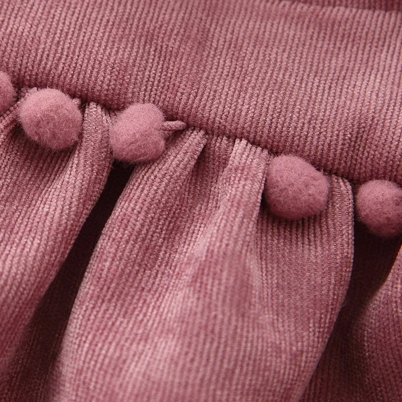 Close-up of pom-pom trim on corduroy dress