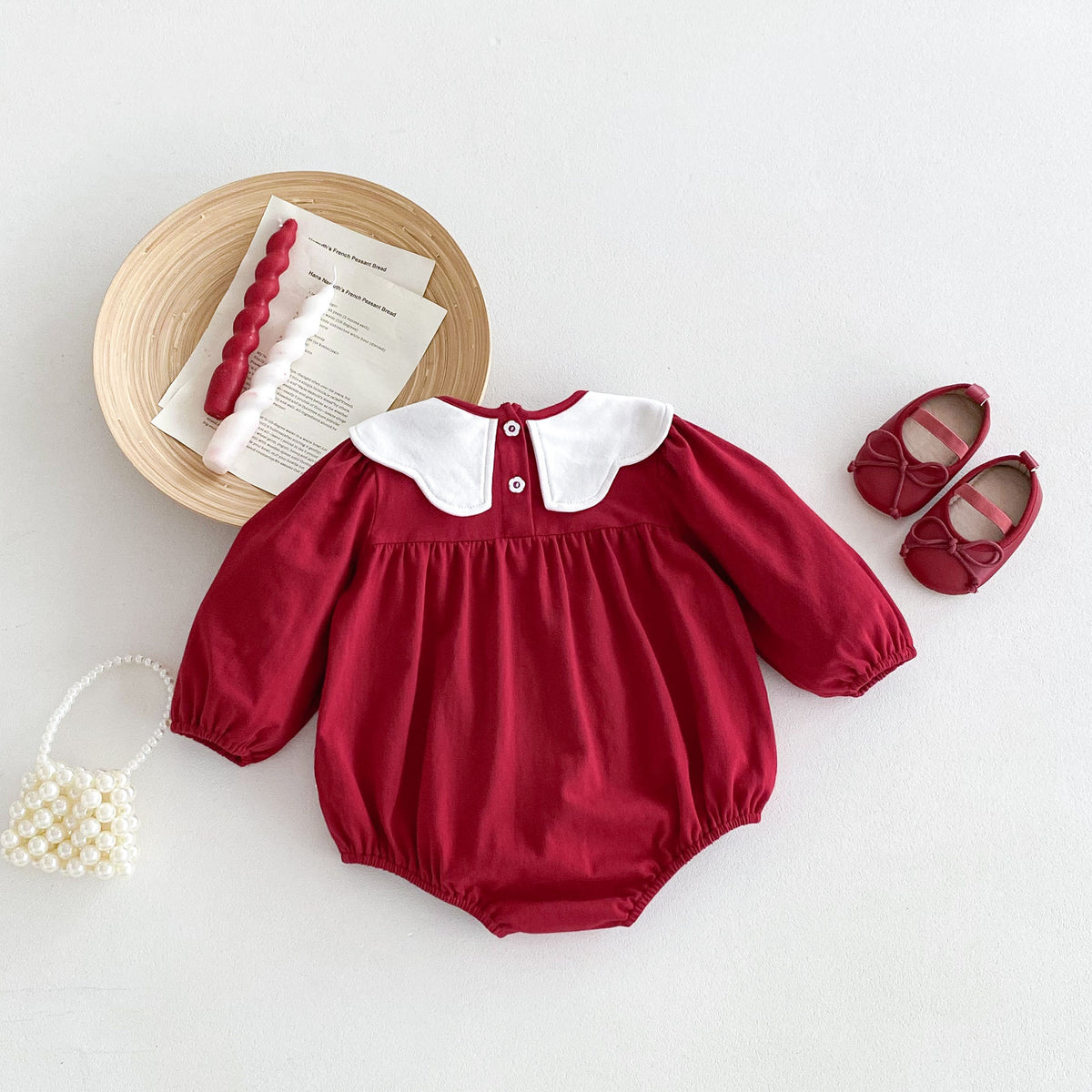 Red baby romper with white scalloped collar, flat lay