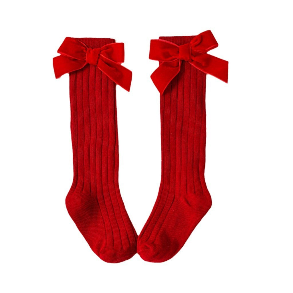 Red velvet bow baby socks on white background