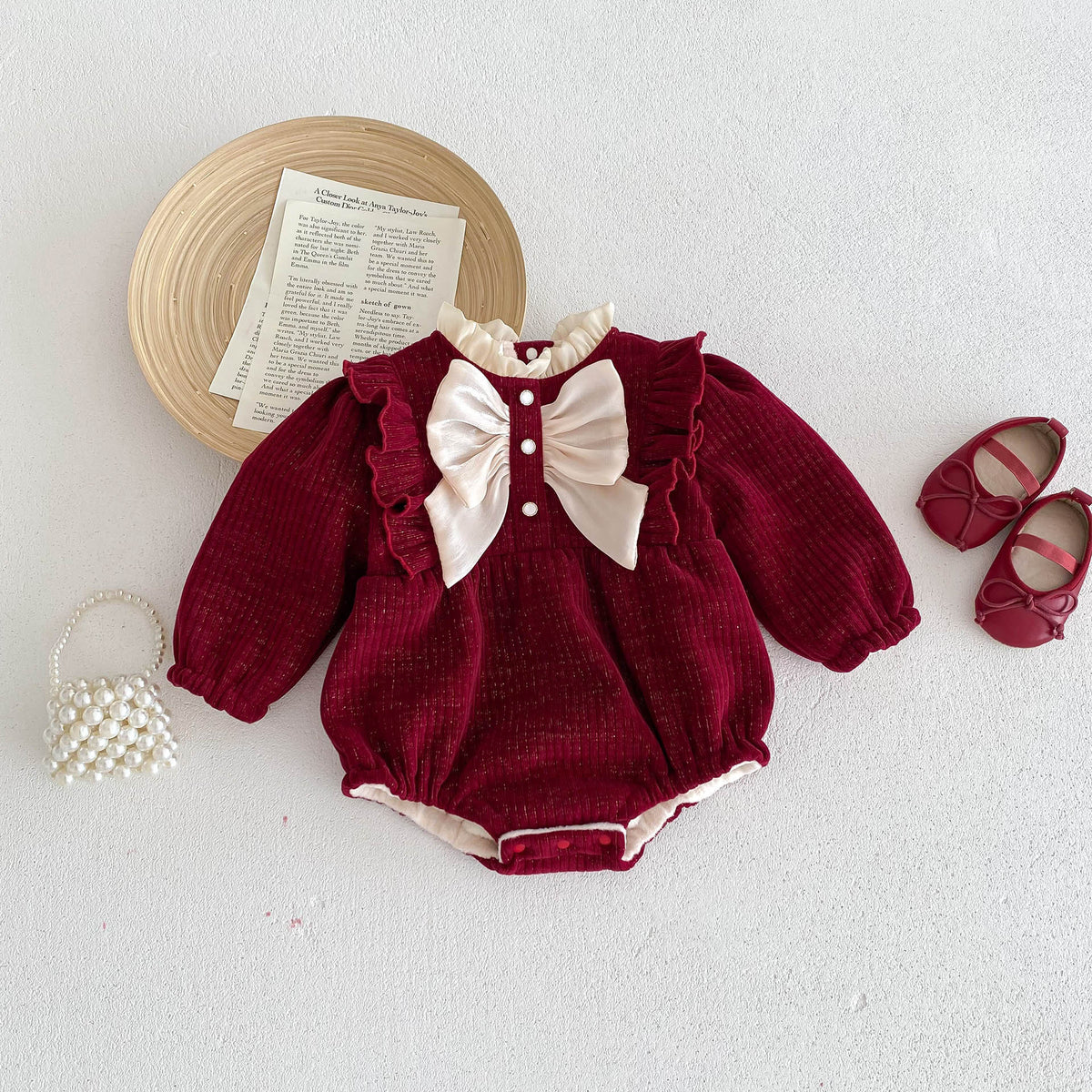 Red bow baby romper laid flat with shoes and bag