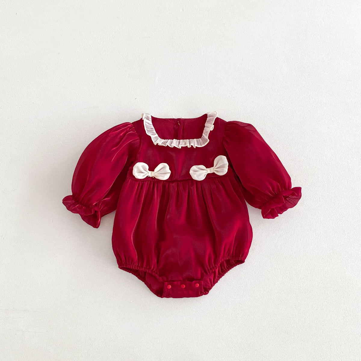 Red romper with cream bows on white background