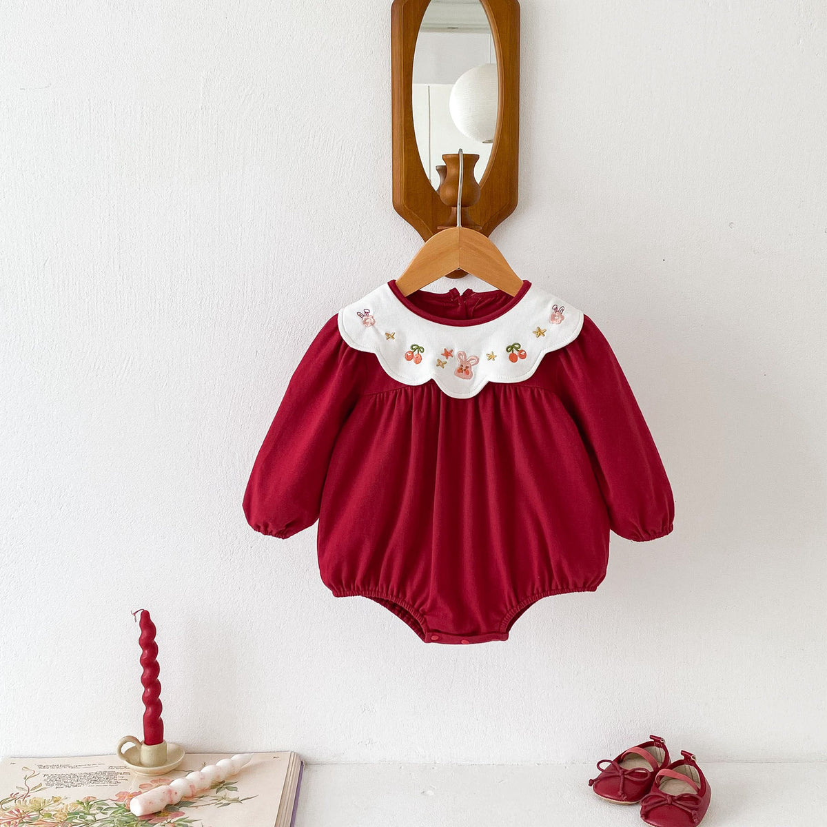 Red long sleeve baby romper with embroidered collar on a hanger