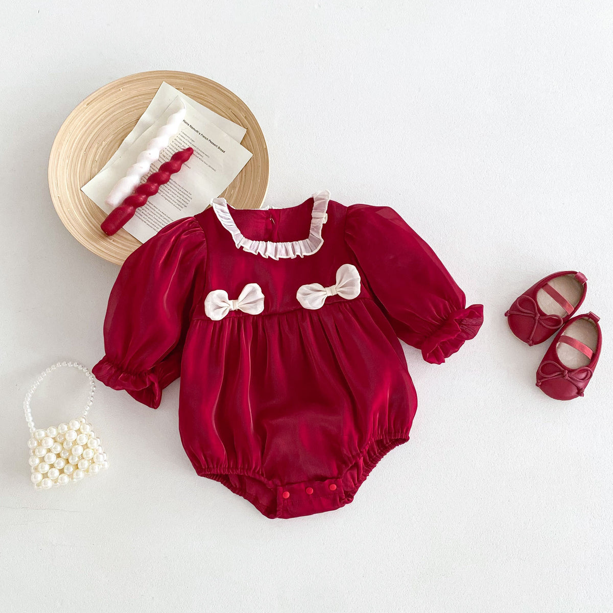 Red lace collar baby romper with bows laid flat with shoes