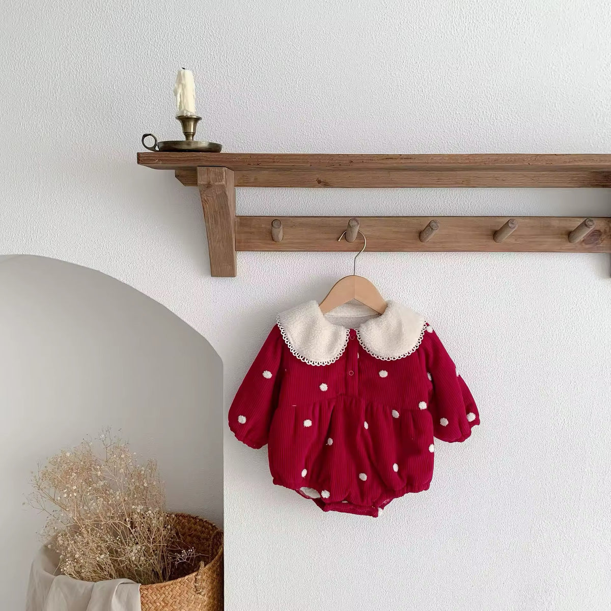 Red polka dot baby romper hanging on a wooden peg rail