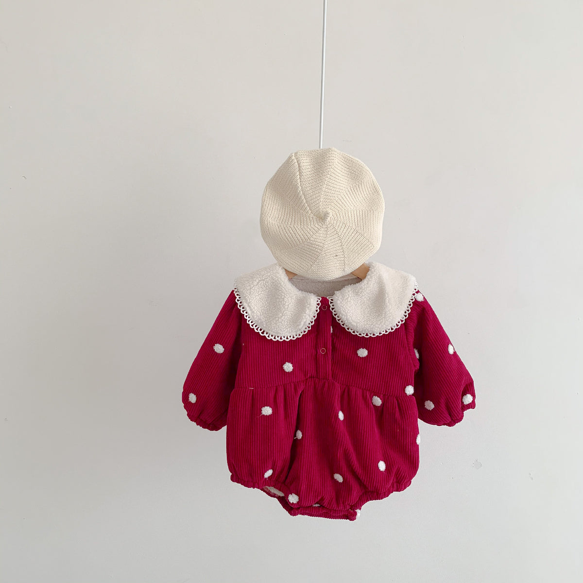 Red corduroy baby romper with white pom-pom polka dots, lace collar and cream beret