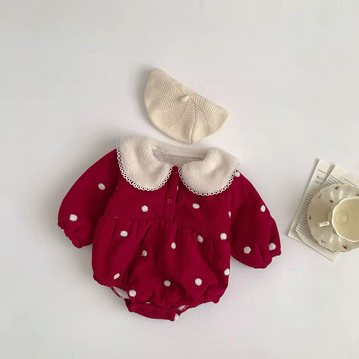 Red polka dot baby romper with fleece-lined Peter Pan collar, flat lay