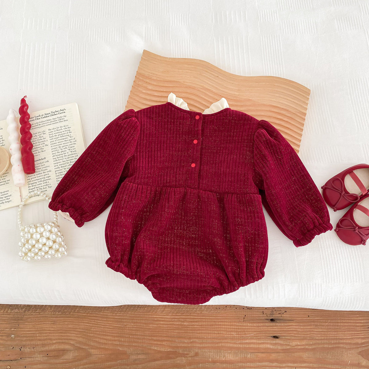 Back view of red romper with buttons on a wooden table