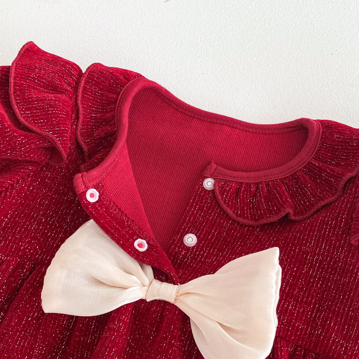 Close-up of button placket and bow on red romper