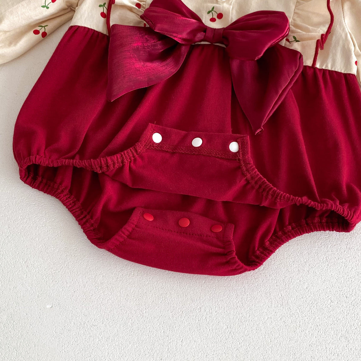 Close-up of red velvet bow and snaps on romper