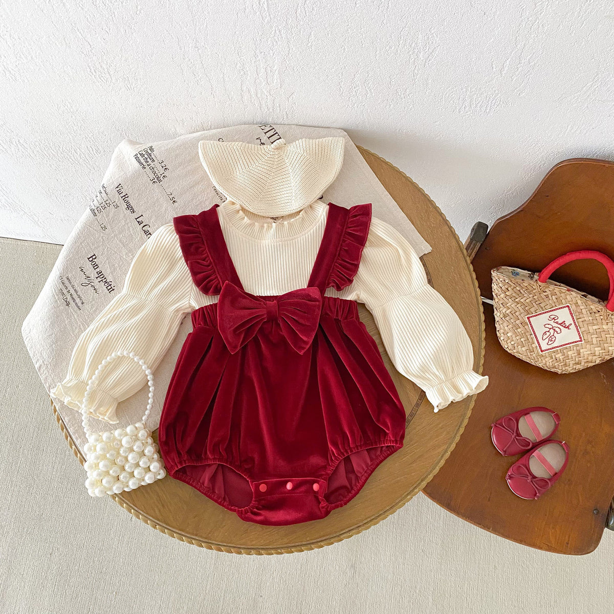 Red velvet romper with ruffle blouse laid flat with shoes and bag