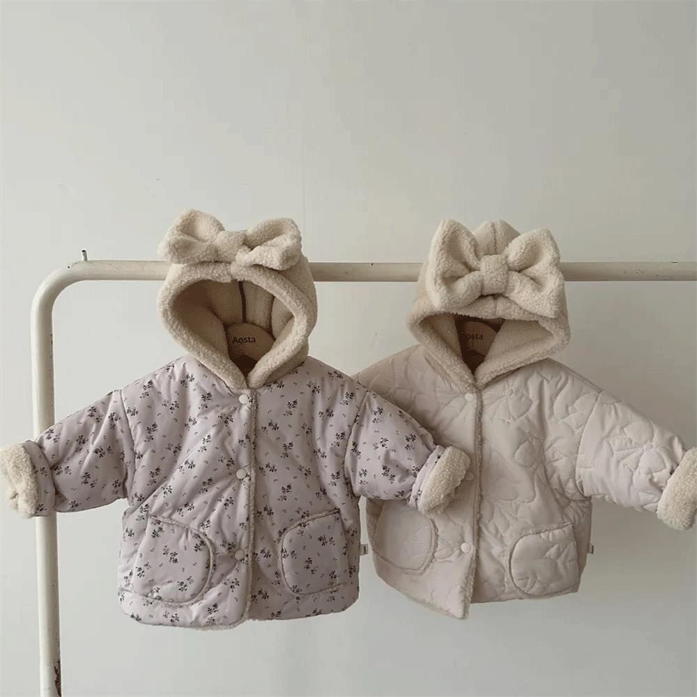 Floral and beige reversible hooded baby jackets on a clothes rail