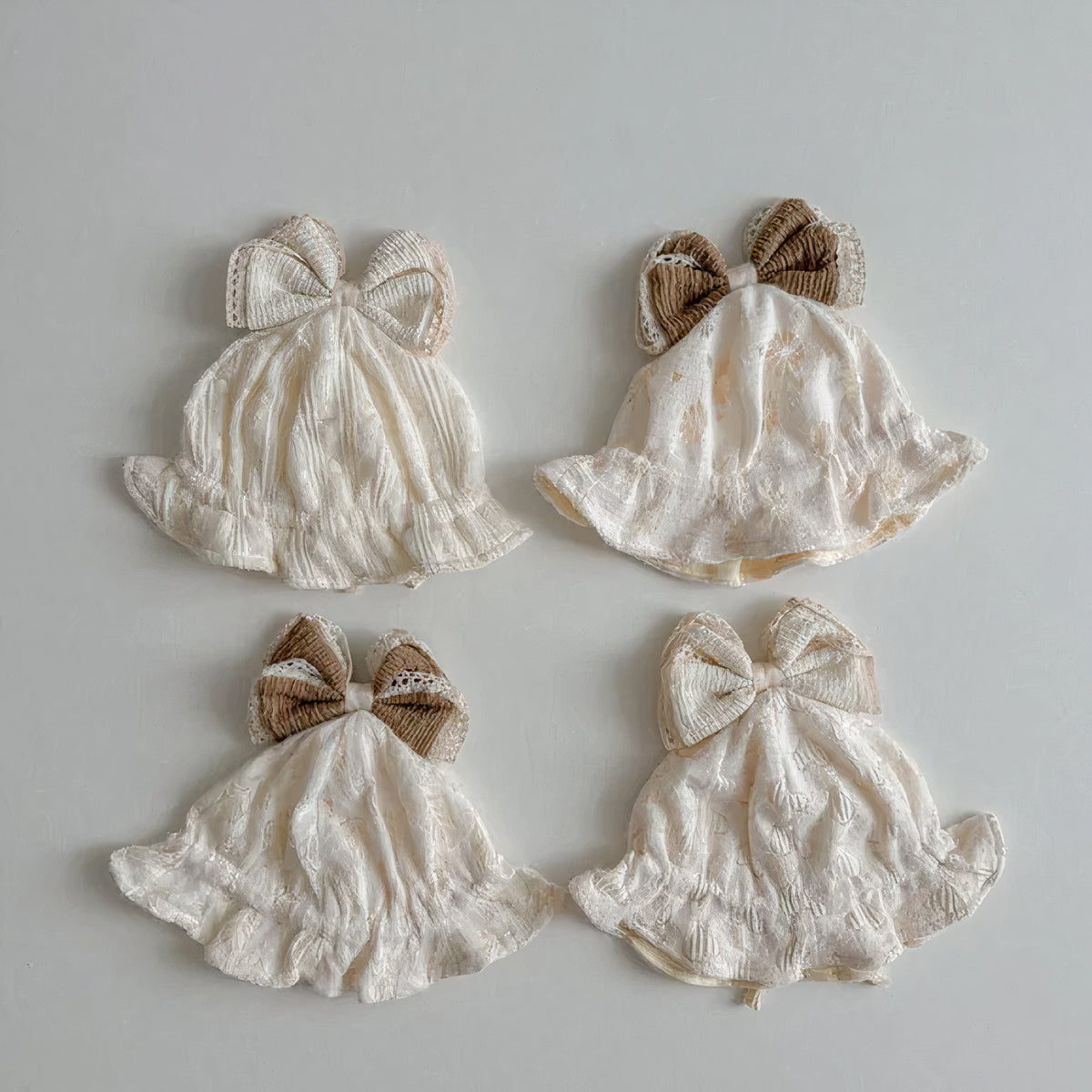 Four cream baby sun hats with brown and cream ribbon bows