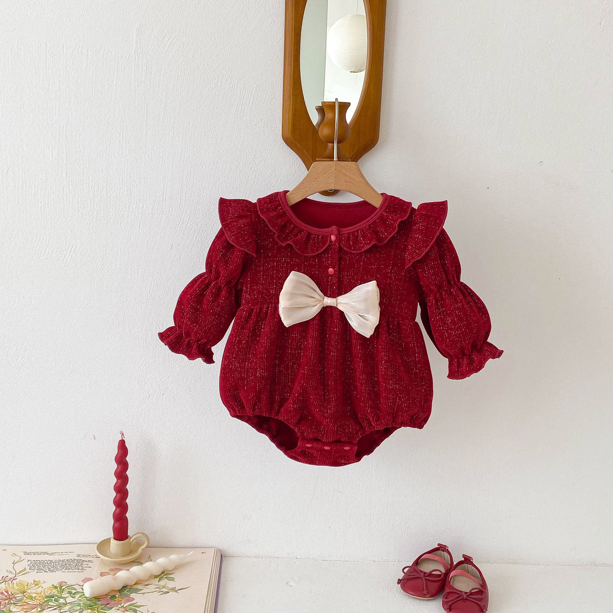 Ruby red ruffle baby romper with cream bow on a hanger