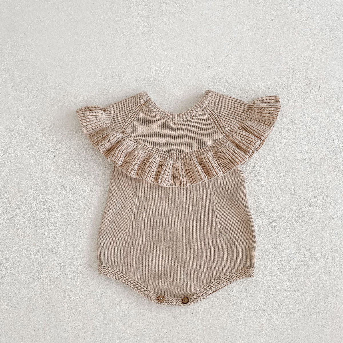 Sleeveless ruffle collar knit baby romper on plain background
