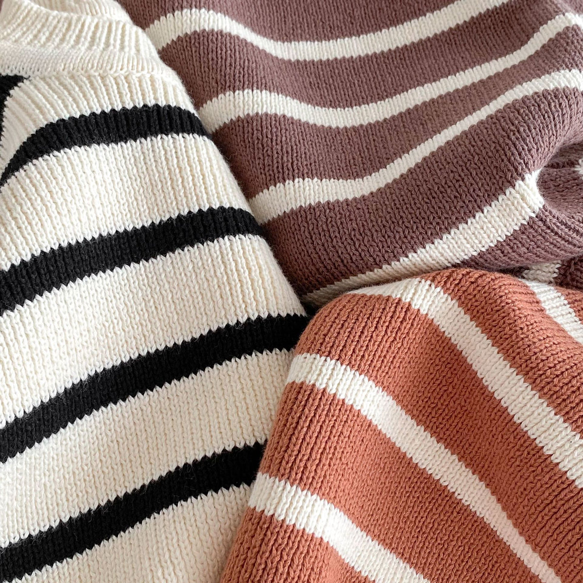 Close-up of soft ribbed knit stripes in black, plum and rust