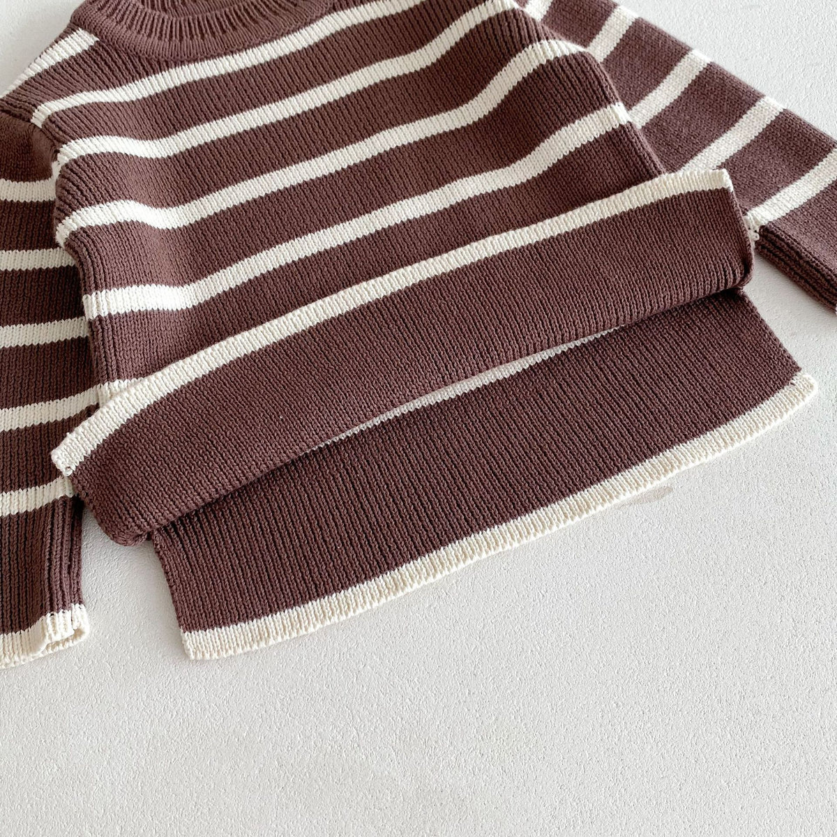 Close-up of side slit hem on plum striped knit sweater