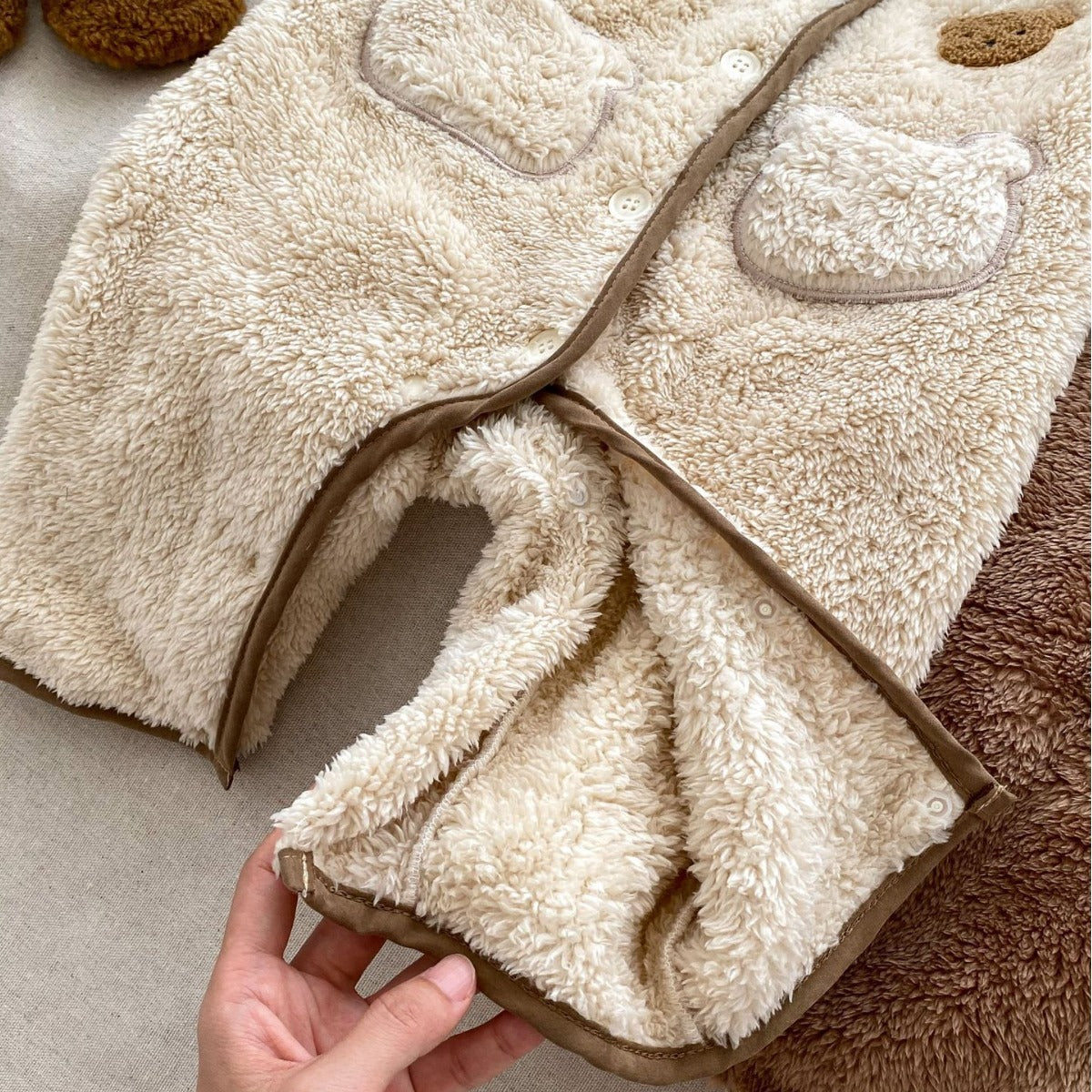 Hand showing soft inside of teddy fleece jumpsuit