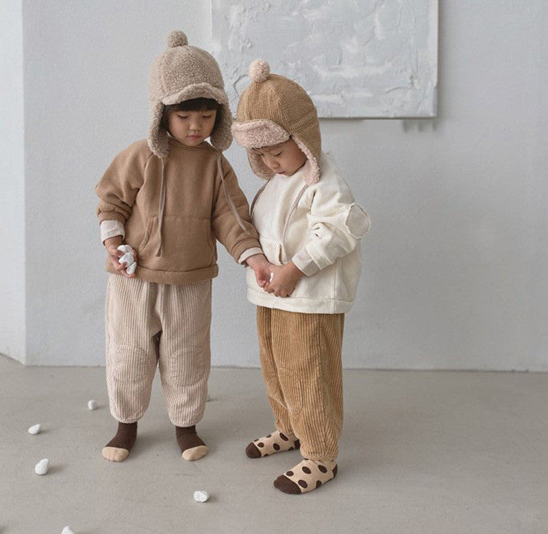 Two toddlers wearing corduroy carrot pants and hats