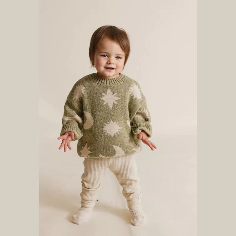 Toddler in an olive sun and moon knit sweater with cream leggings