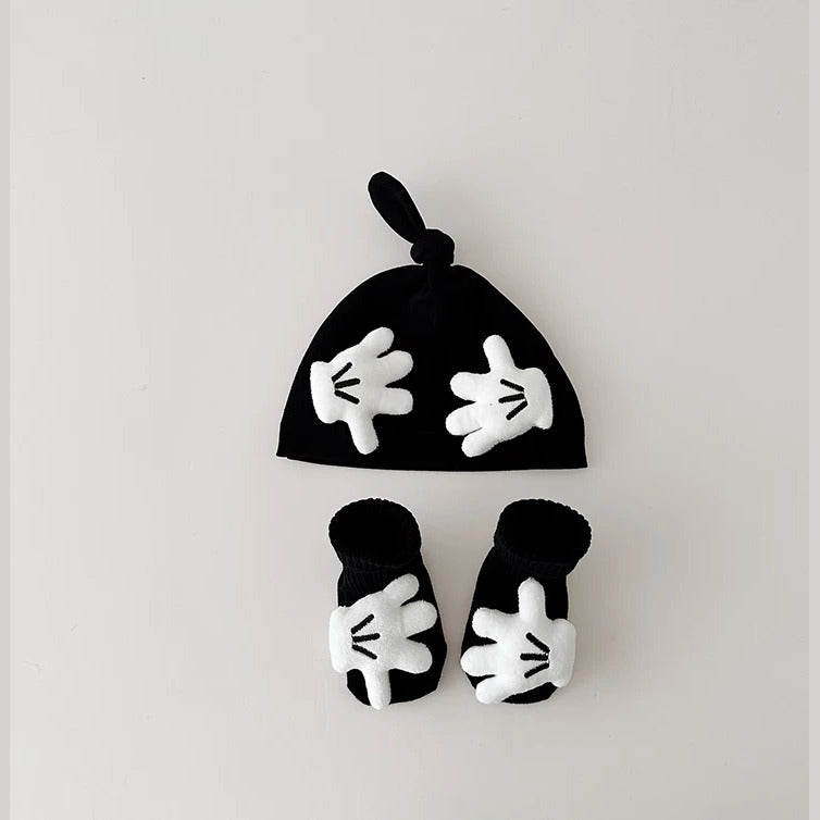 Black knot baby beanie and socks with white cartoon hands, flat lay