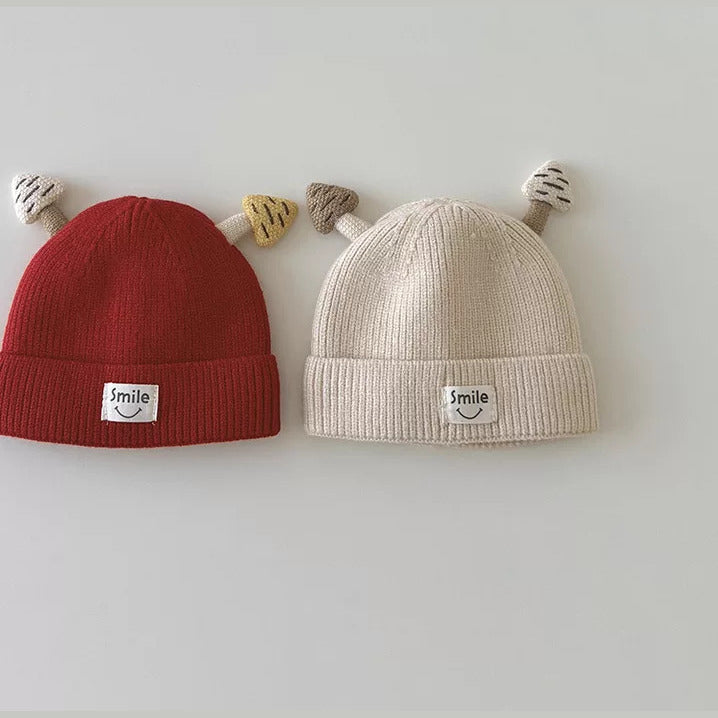Cherry red and cream mushroom knit beanies side by side