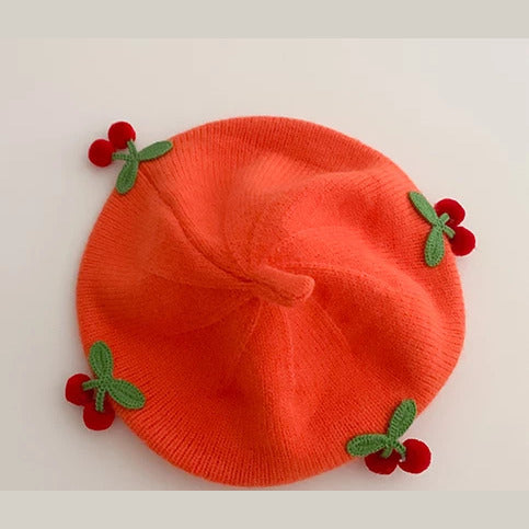 Tangerine knit baby beret with crochet cherries, flat lay