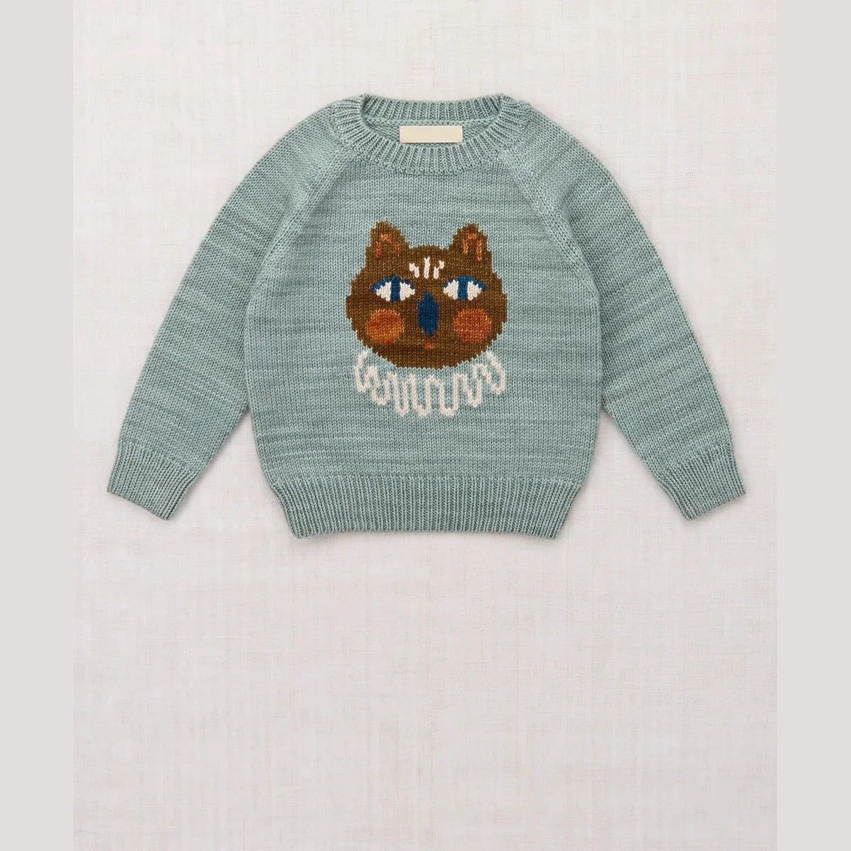 Misty blue kids knit sweater with a brown cat face, flat lay