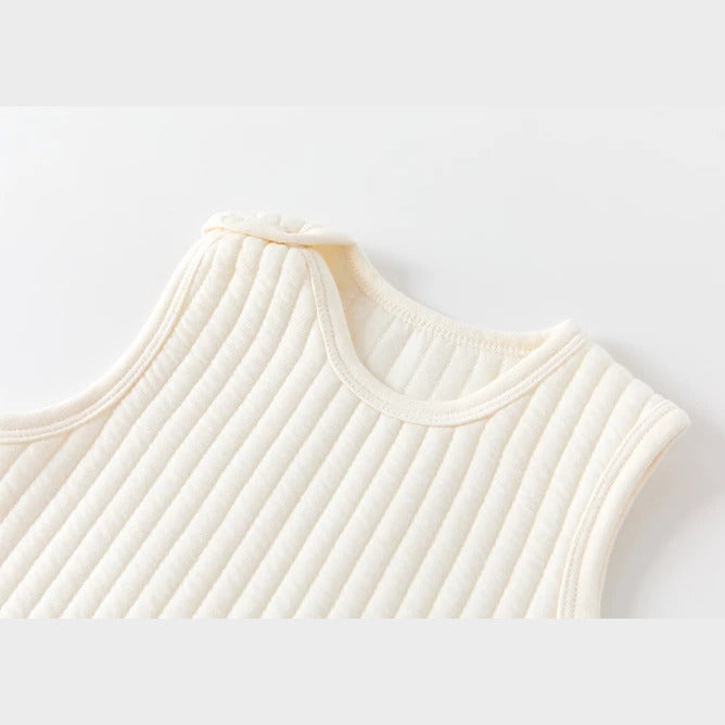 Close-up of the bound neckline and shoulder snap on a cream quilted romper