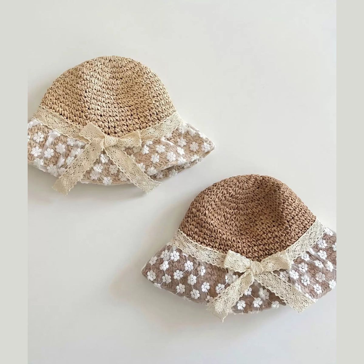 Two lace-brim straw bucket hats for toddlers in natural and caramel