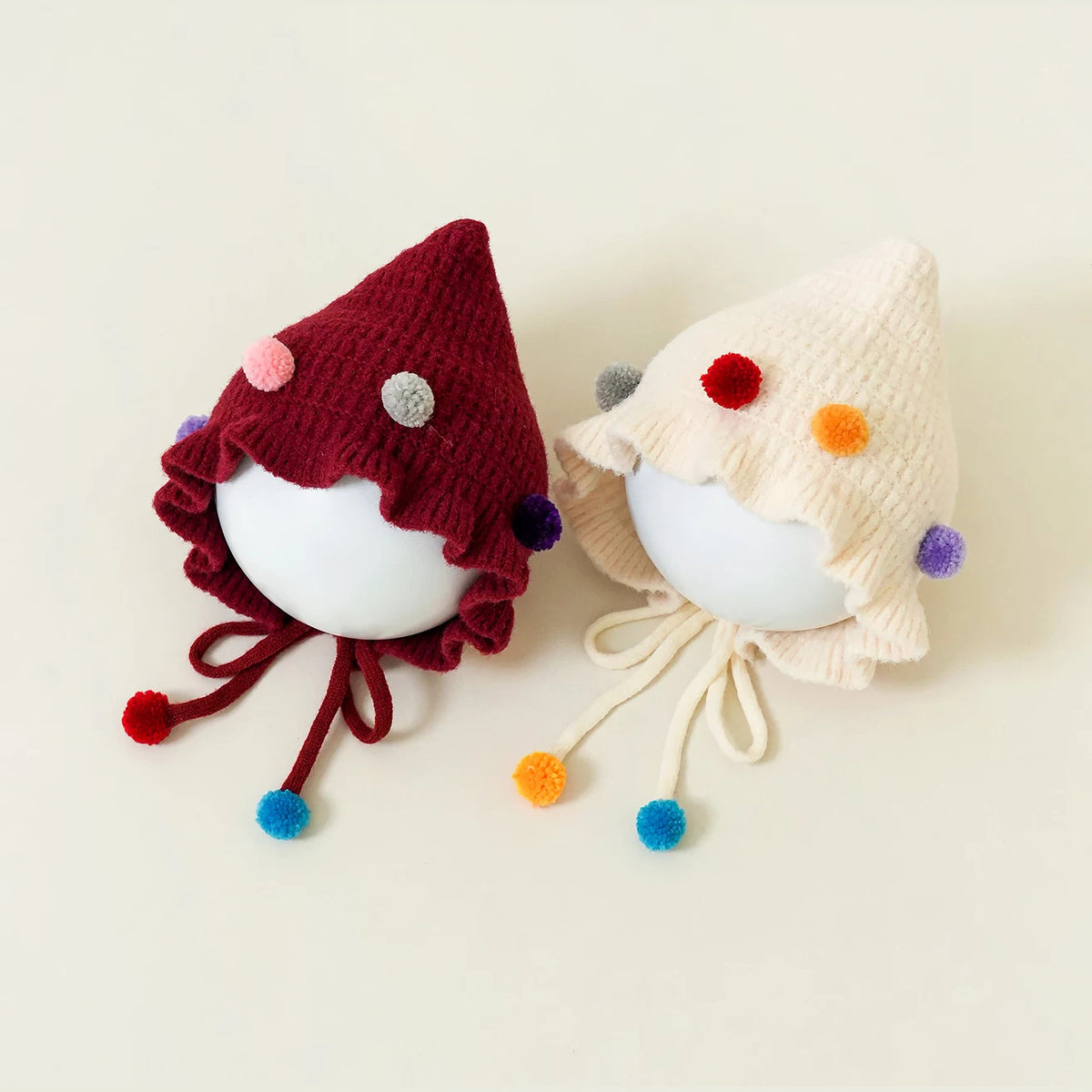 Pair of confetti pom-pom knit bonnets with ruffled brims