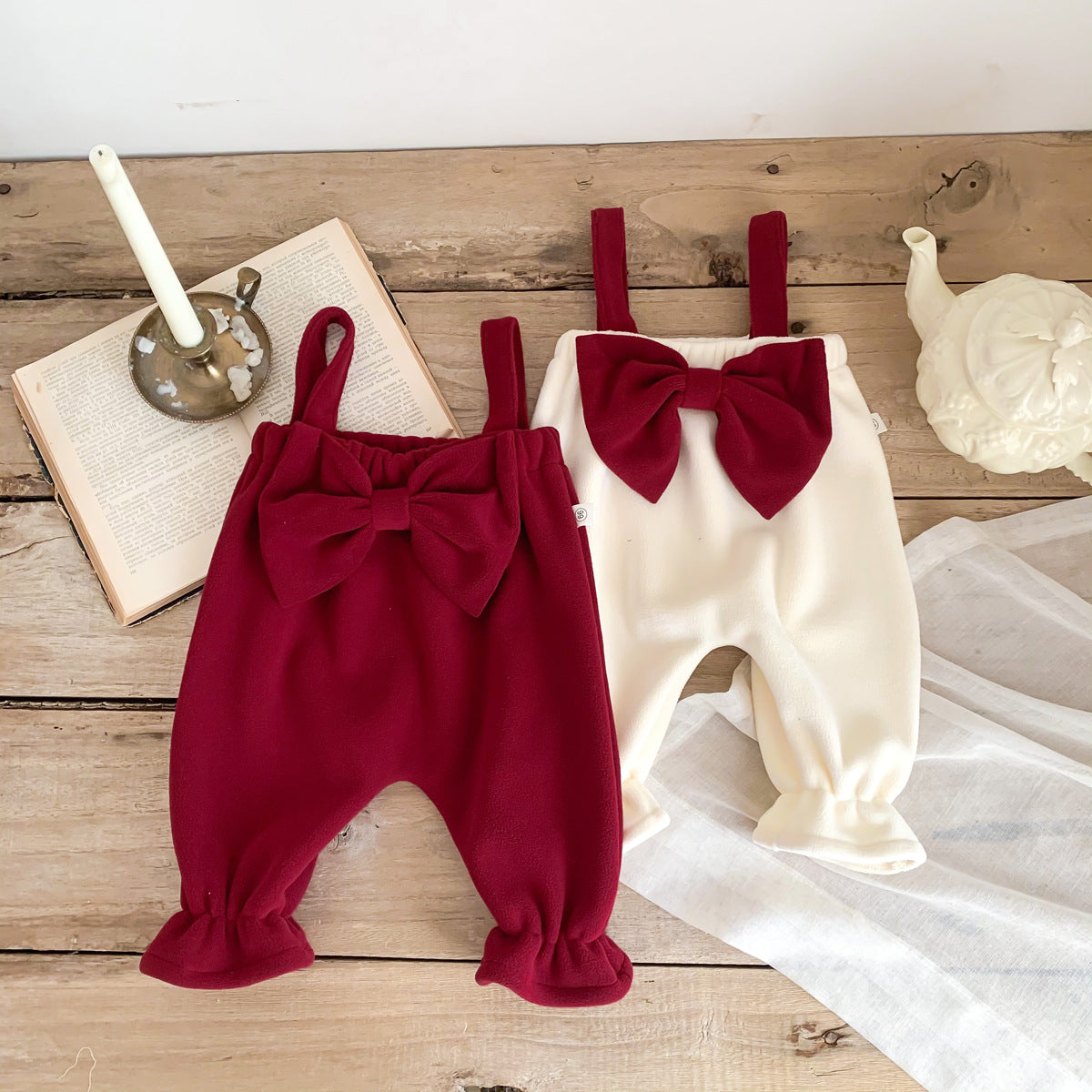 Wine red and white velvet bow overalls laid on a table