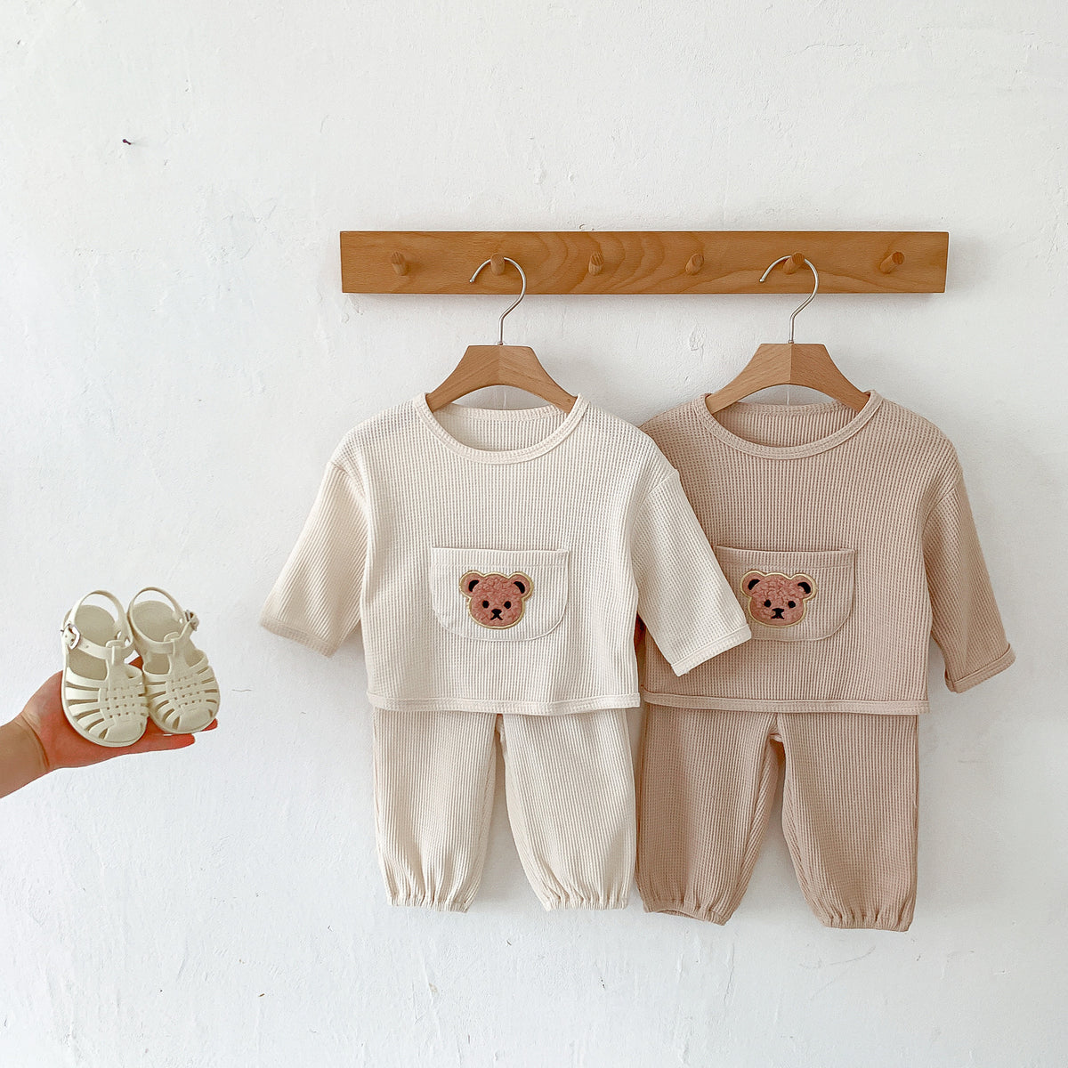 Cream and taupe waffle bear sets hanging on a peg rail
