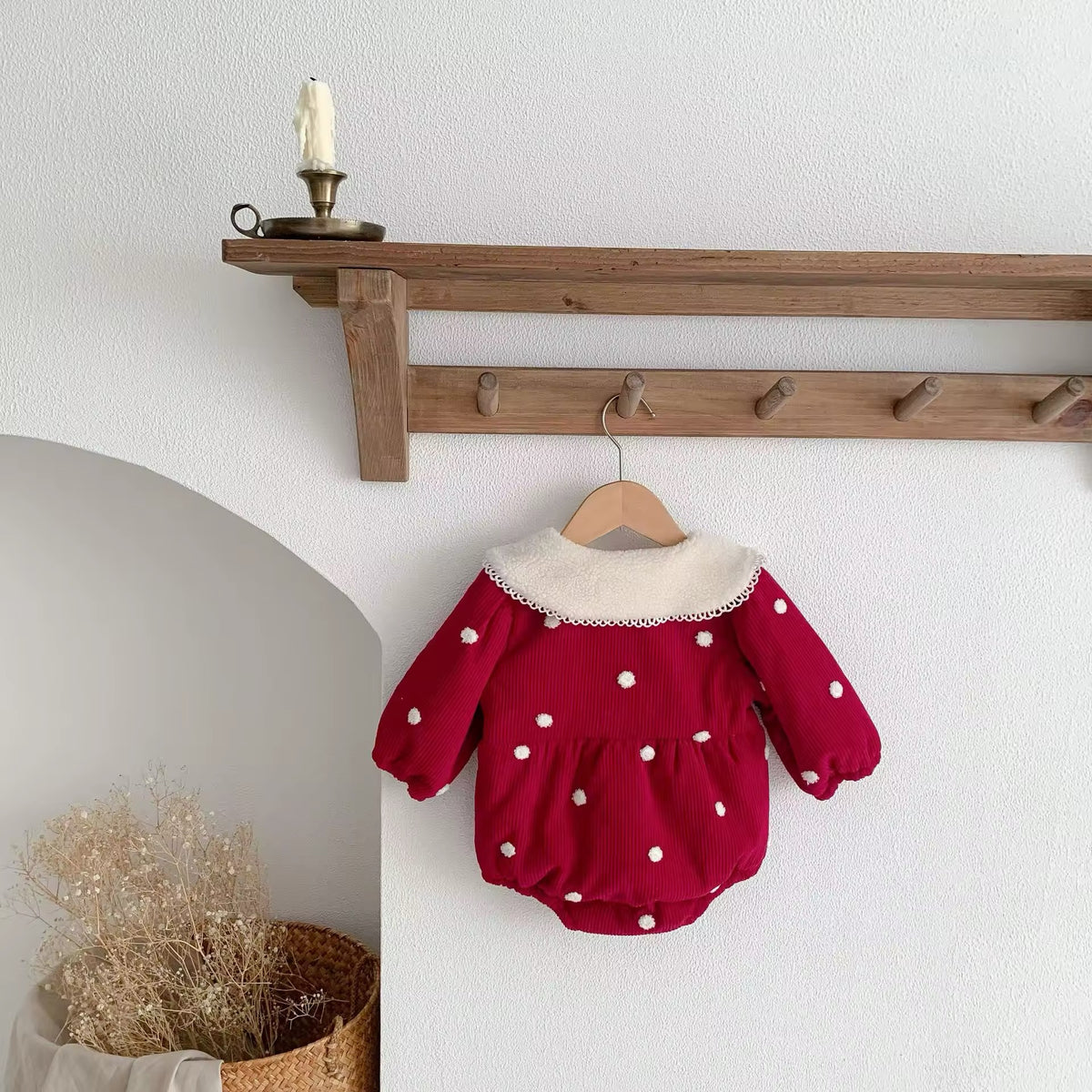 Warm red baby romper with cream Peter Pan collar on a hanger