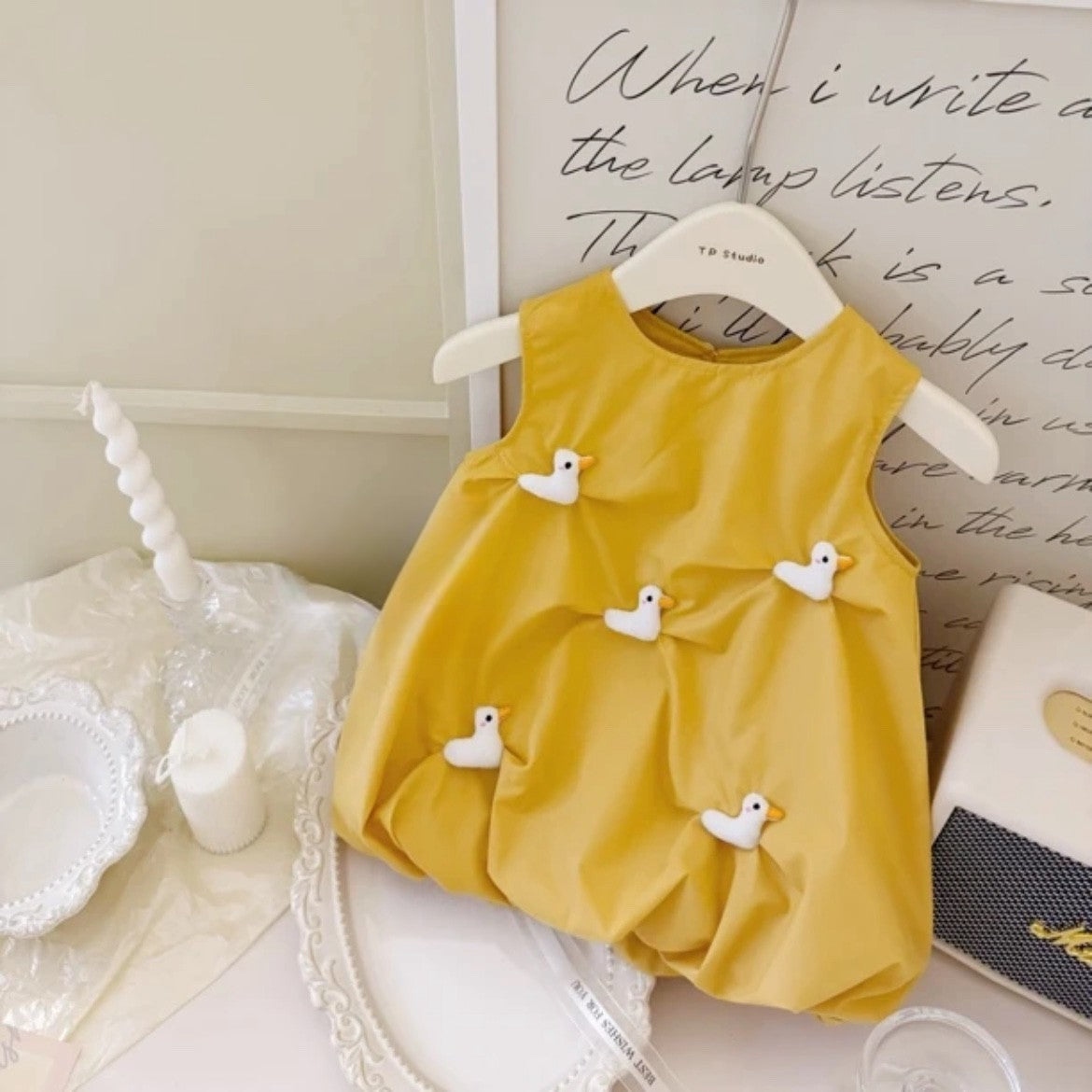 Yellow sleeveless dress with 3D white ducks on a hanger