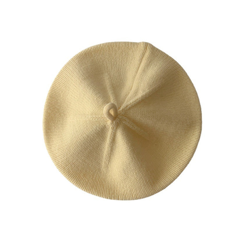 Yellow knitted baby beret on white background