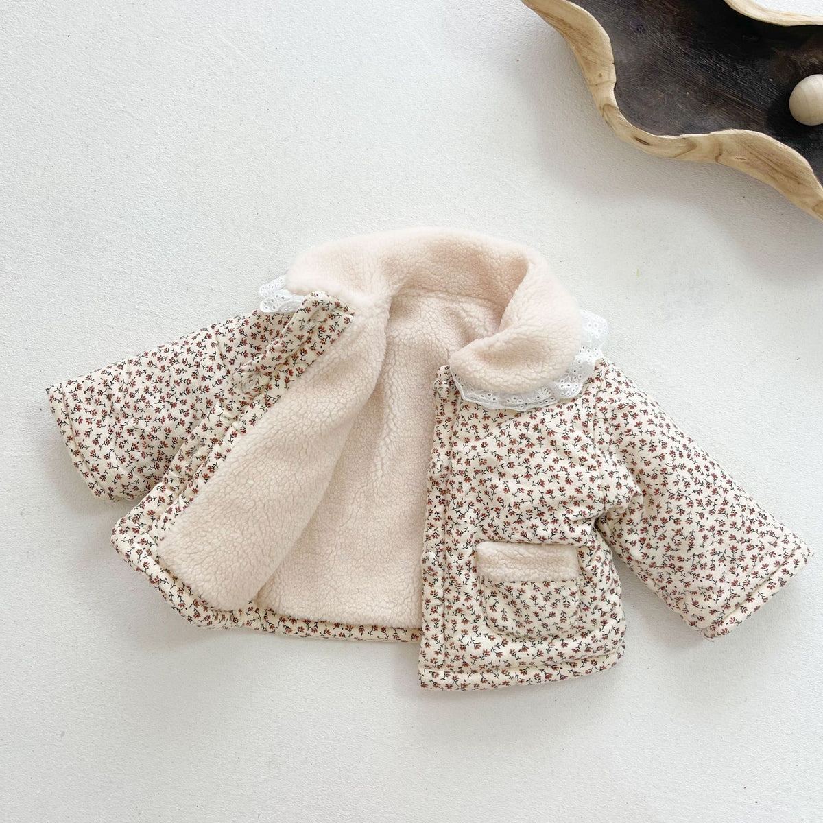 Baby girl wearing a floral quilted jacket with white lace collar