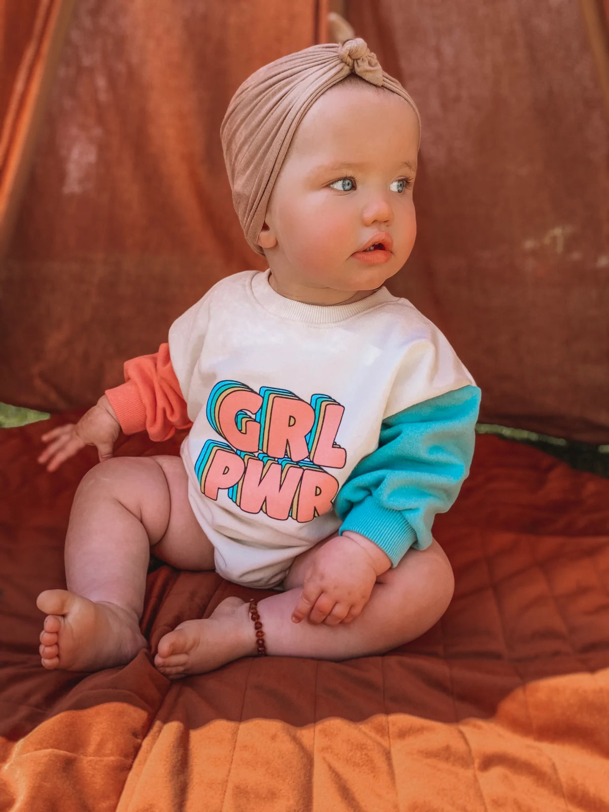 Baby in GRL PWR romper with headband