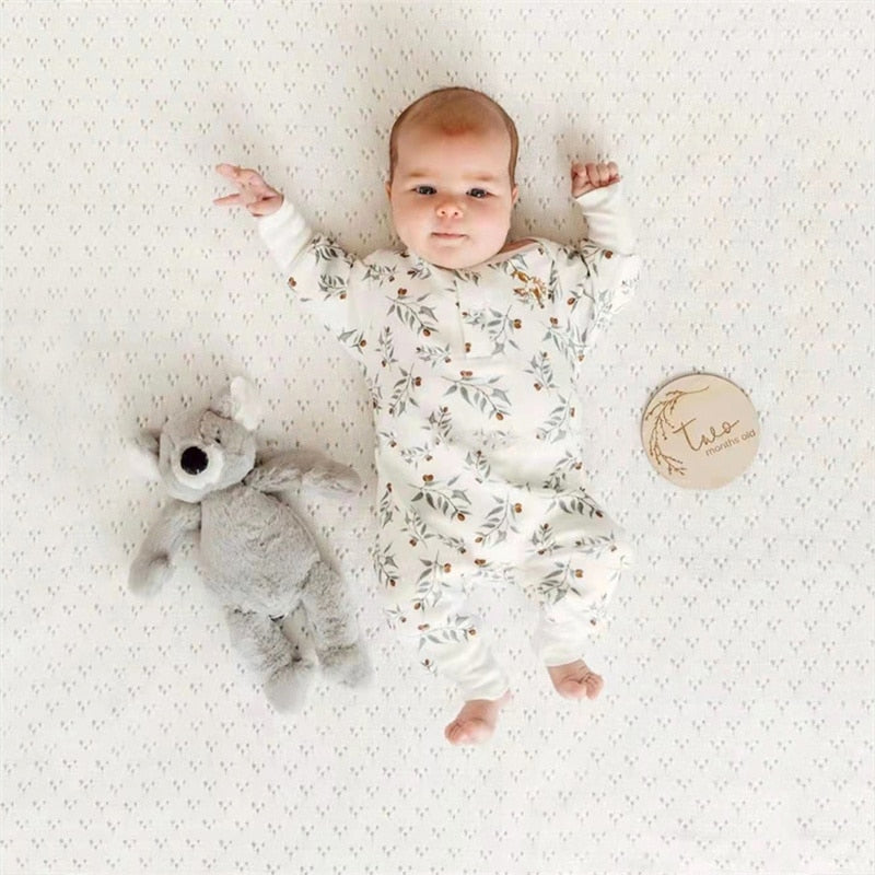 Baby lying in floral print romper with teddy