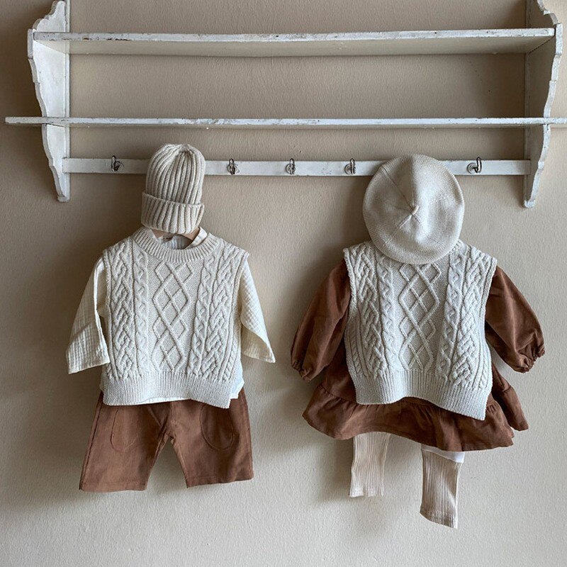Cable knit vests hanging on a rail with outfits