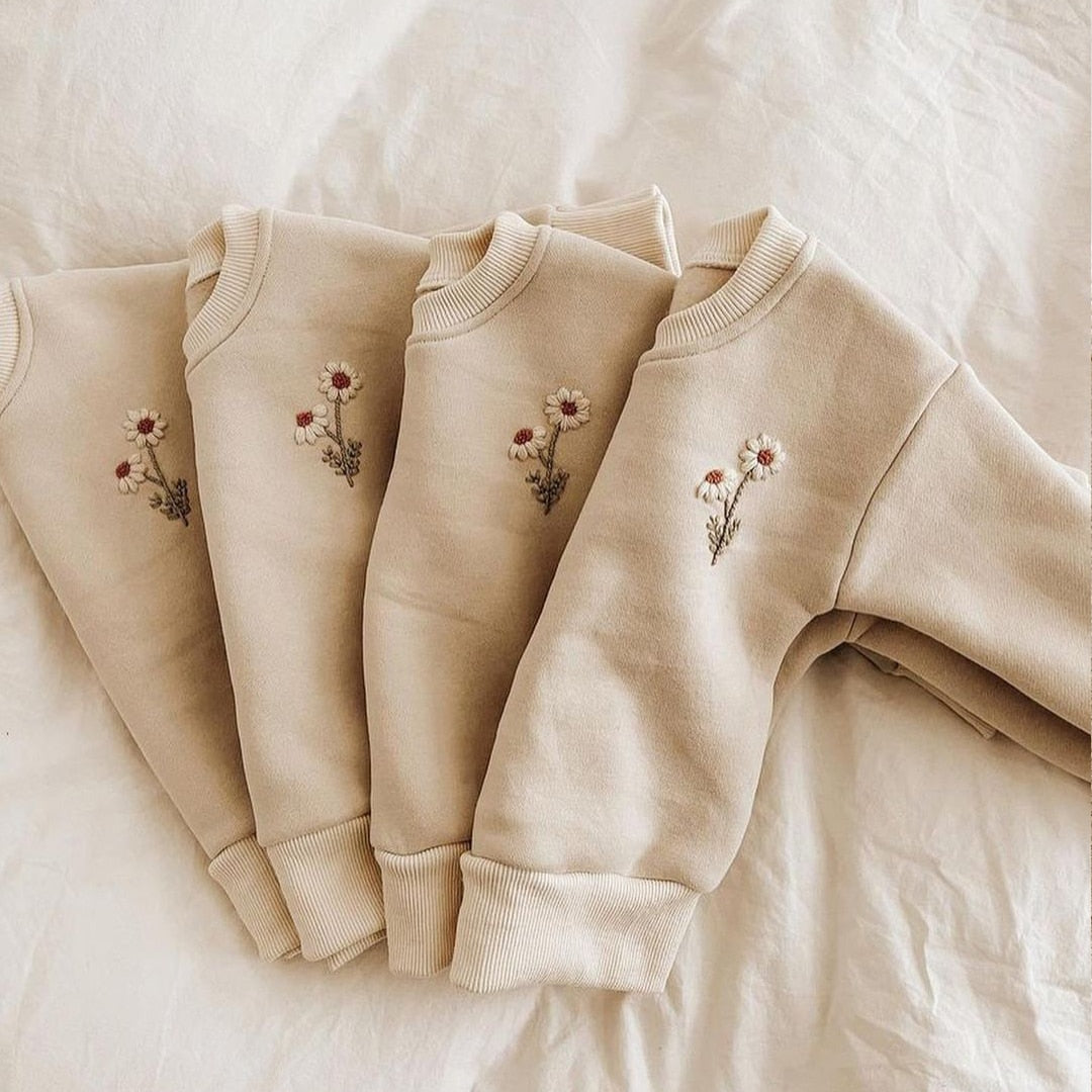Row of folded daisy embroidered sweatshirts