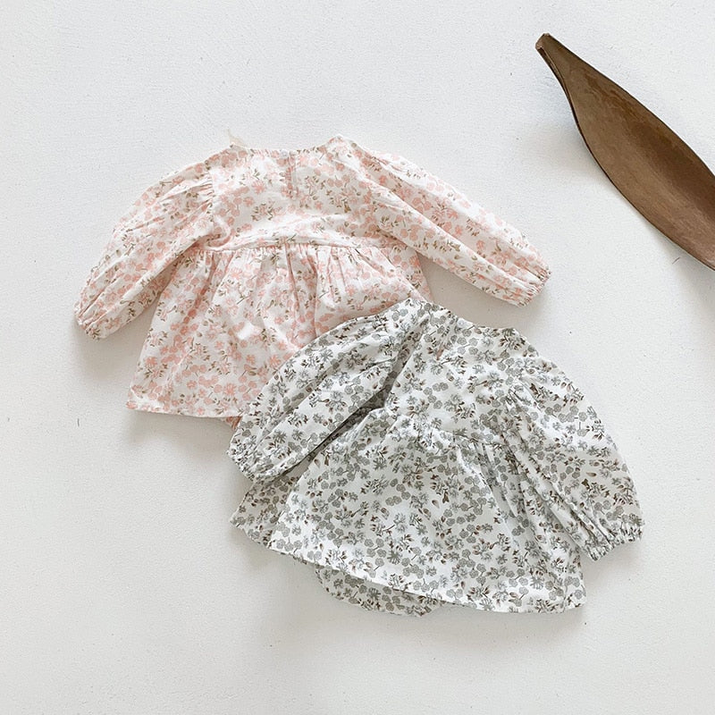 Pink and grey floral dresses laid flat with leaf