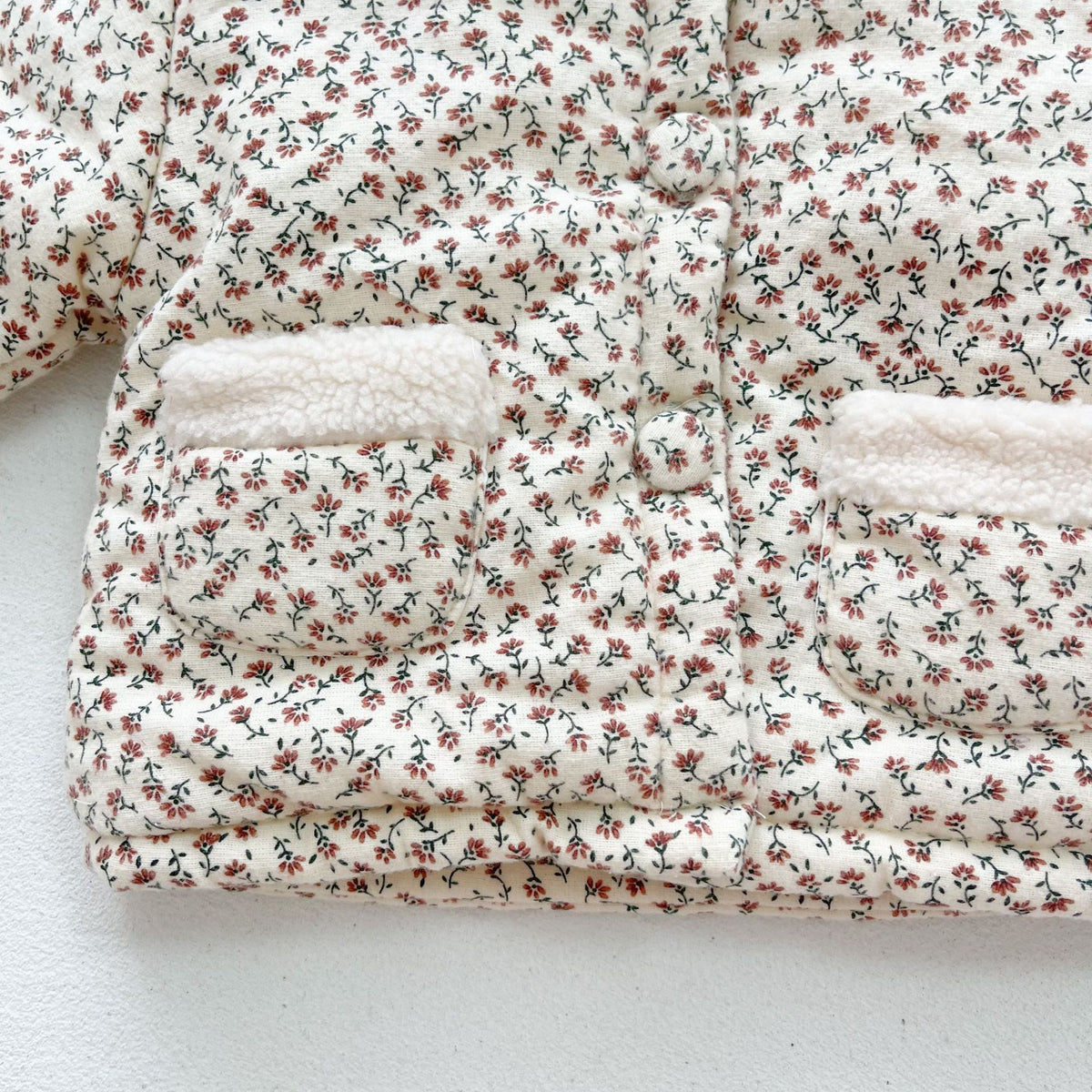 Floral quilted baby jacket with eyelet lace collar, front view