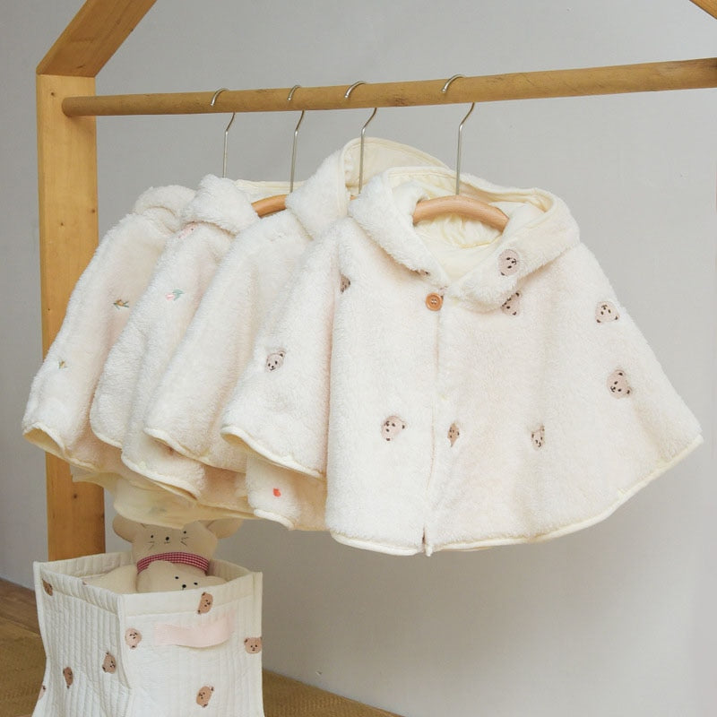 Cream fur-lined hooded baby capes on a clothes rail