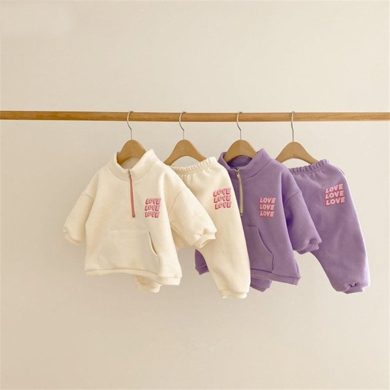 White and purple LOVE half-zip sets on hangers
